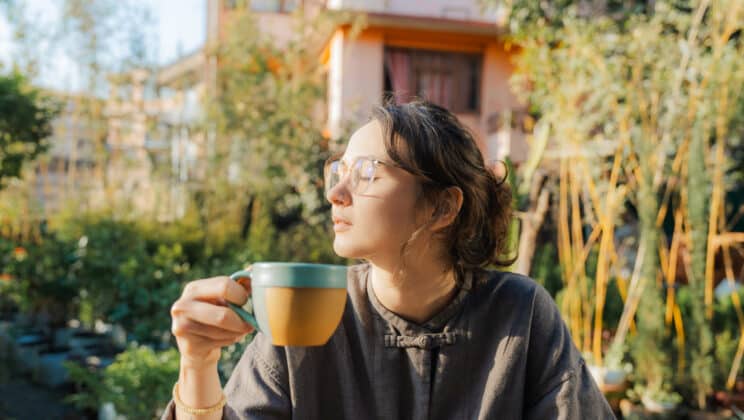 Woman sitting with the cup of hot beverage enjoying the sunshine