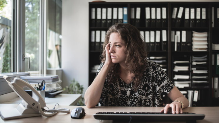 Caucasian woman sitting at a desk looking out the window