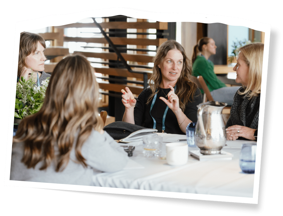four women at a table speaking to each other