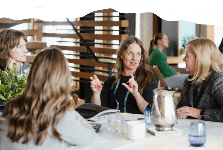 four women at a table speaking to each other